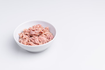 Canned tuna in a white bowl, isolated on white background; copy space, soft light, studio shot