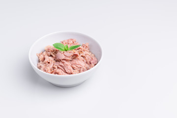 Canned tuna in a white bowl, isolated on white background; copy space, soft light, studio shot