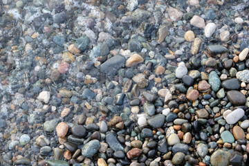 Abstract image of the water ripples over the stone pebbles in the Mediterranean Sea. Gray abstract background