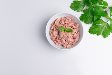 Canned tuna in a white bowl, isolated on white; empty open tuna tin on a white background; copy space, soft light, studio shot