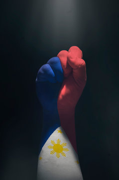 Raised fist of a Philippine flag. Filipino hand showing a symbol of strong, independence. Close grip hand painted in a Filipino flag in black isolated background.