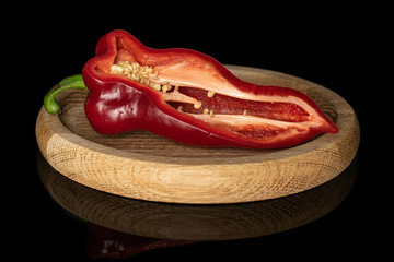One half of sweet red bell pepper on bamboo plate isolated on black glass