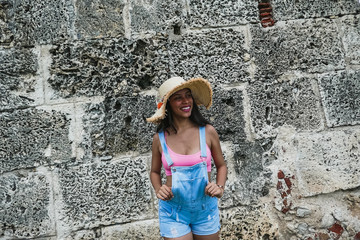 Outdoor fashion photo portrait of a beautiful young, tender and modern Latina model posing and smiling during summer trips.