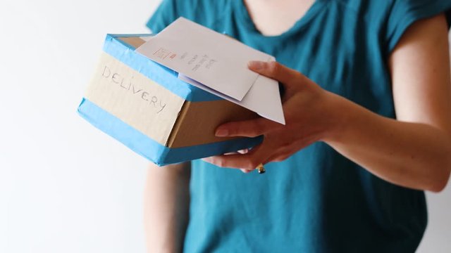 woman with delivery parcel and envelopes in her hands giving them to a recipient