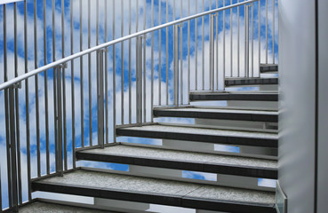 柵と手すりのある屋外螺旋階段と白い雲のある青空