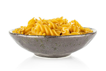 Lot of whole dry brown wholegrain fusilli in dark ceramic bowl isolated on white background