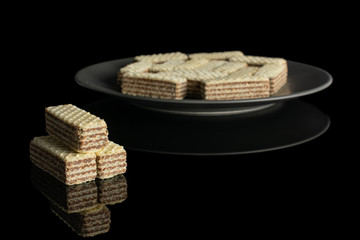 Lot of whole crispy beige hazelnut wafer cookie on gray ceramic plate isolated on black glass