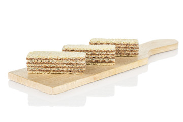 Group of three whole crispy beige hazelnut wafer cookie on small wooden cutting board isolated on white background