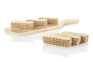 Group of six whole crispy beige hazelnut wafer cookie on small wooden cutting board isolated on white background