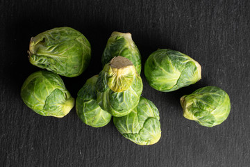 Group of eight whole fresh green brussels sprout flatlay on grey stone