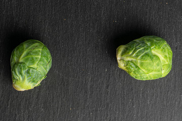 Group of two whole fresh green brussels sprout flatlay on grey stone