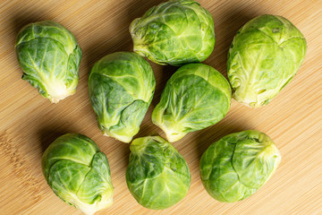 Group of eight whole fresh green brussels sprout flatlay on light wood