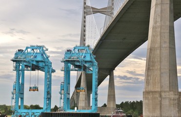 Fototapeta premium Port cargo cranes are transported on river under bridge using barge