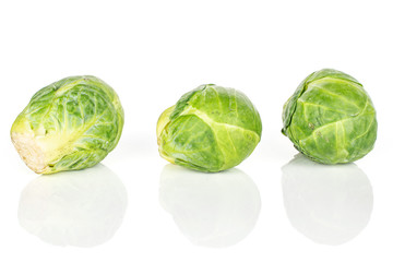 Group of three whole fresh green brussels sprout isolated on white background