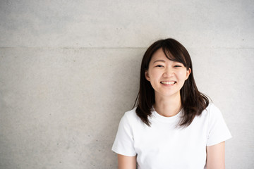 コンクリート壁の前で微笑む女性