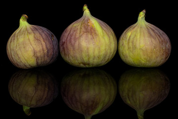 Group of three whole sweet purple fig isolated on black glass