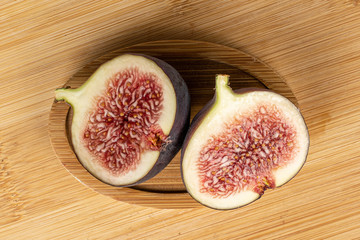 Group of two halves of sweet purple fig flatlay on light wood