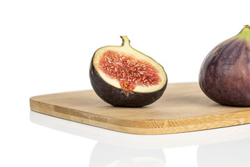 Group of one whole one half of sweet purple fig on bamboo cutting board isolated on white background
