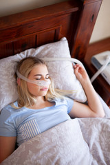 Obraz na płótnie Canvas Sleep apnea and cpap machine female sleeping in blue