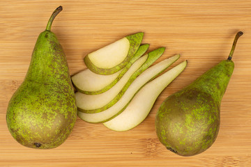 Group of two whole five slices of fresh green pear flatlay on light wood