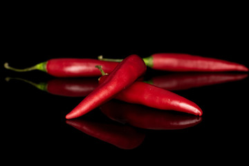 Group of four whole hot red chili cayenne isolated on black glass