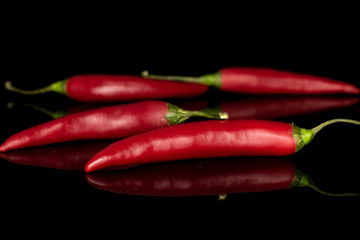 Group of four whole hot red chili cayenne isolated on black glass