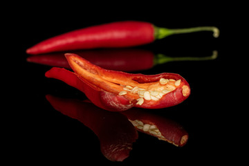 Group of two whole hot red chili cayenne one opened isolated on black glass