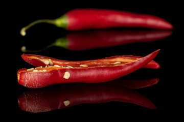 Group of two whole hot red chili cayenne one opened isolated on black glass
