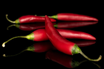 Group of four whole hot red chili cayenne crossed isolated on black glass
