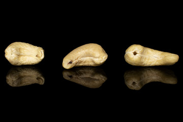 Group of three whole brown nut cashew isolated on black glass