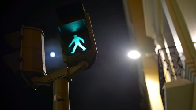 Toma noctura de un sem&aacute;foro peatonal y al fondo la luna