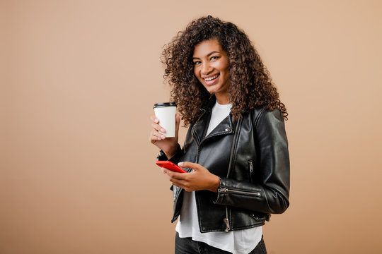 happy smiling black girl with phone and coffee to go cup isolated over brown