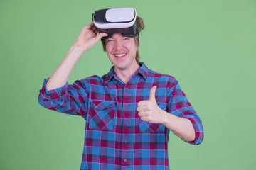 Happy young hipster man removing virtual reality headset and giving thumbs up