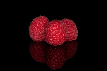 Group of three whole fresh red raspberry isolated on black glass