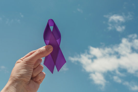 hand holding purple ribbon over blue sky, Alzheimer's disease, Pancreatic cancer, Epilepsy awareness, world cancer day