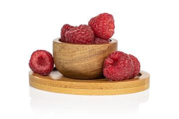 Lot of whole fresh red raspberry on round bamboo coaster in bamboo bowl isolated on white background