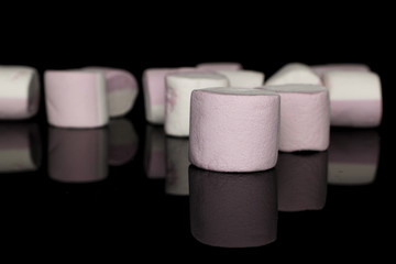 Lot of whole sweet pastel marshmallow front focus isolated on black glass