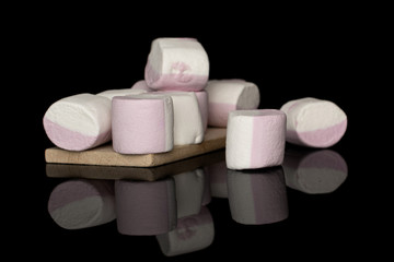 Lot of whole sweet pastel marshmallow on wooden cutting board isolated on black glass