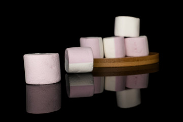 Group of six whole sweet pastel marshmallow on round bamboo coaster isolated on black glass