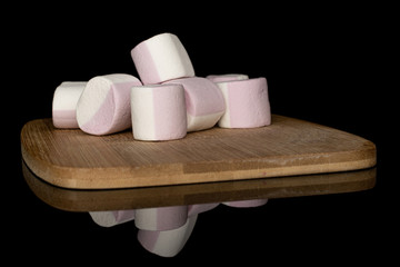 Group of six whole sweet pastel marshmallow on bamboo cutting board isolated on black glass