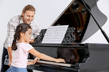 Man teaching little girl to play piano