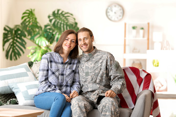 Obraz premium Happy military couple sitting on sofa at home, soldier and wife reunited, family support and patriotism