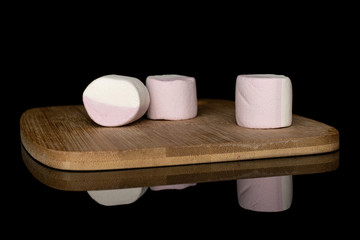 Group of three whole sweet pastel marshmallow on bamboo cutting board isolated on black glass