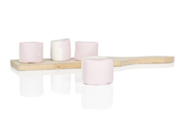 Group of four whole sweet pastel marshmallow on wooden cutting board isolated on white background