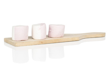 Group of three whole sweet pastel marshmallow on wooden cutting board isolated on white background