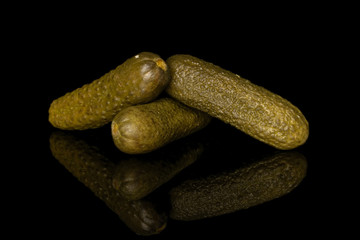 Group of three whole sour green pickle isolated on black glass