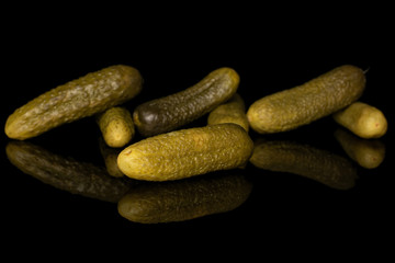 Group of seven whole sour green pickle isolated on black glass