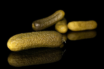 Group of four whole sour green pickle isolated on black glass