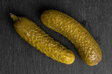 Group of two whole sour green pickle flatlay on grey stone