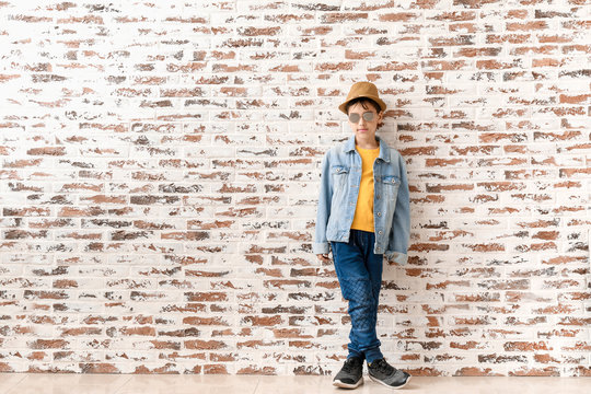 Cute fashionable boy against brick wall